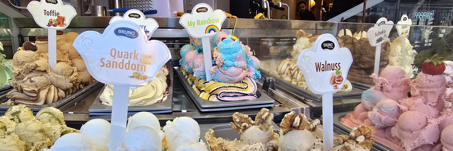 Eine Schaufenstervitrine mit einer großen Auswahl an Eiskreationen, Desserts und süßen Kuchen.
